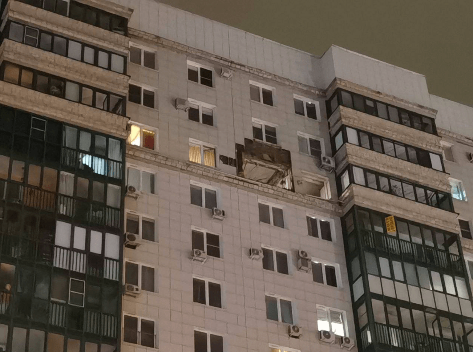A residential building missing an exterior panel on a higher level
