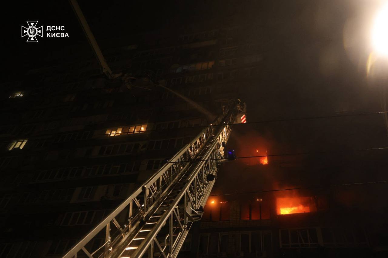 An aerial ladder reaching a blaze higher up in a damaged residential building