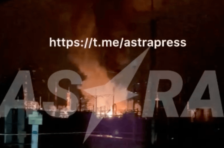 A fire burns at an industrial facility under a black sky