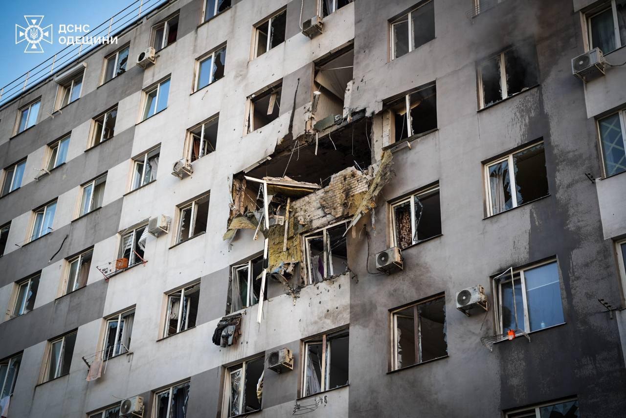 A higher floor of a residential building damaged, with windows near the site of impact shattered.