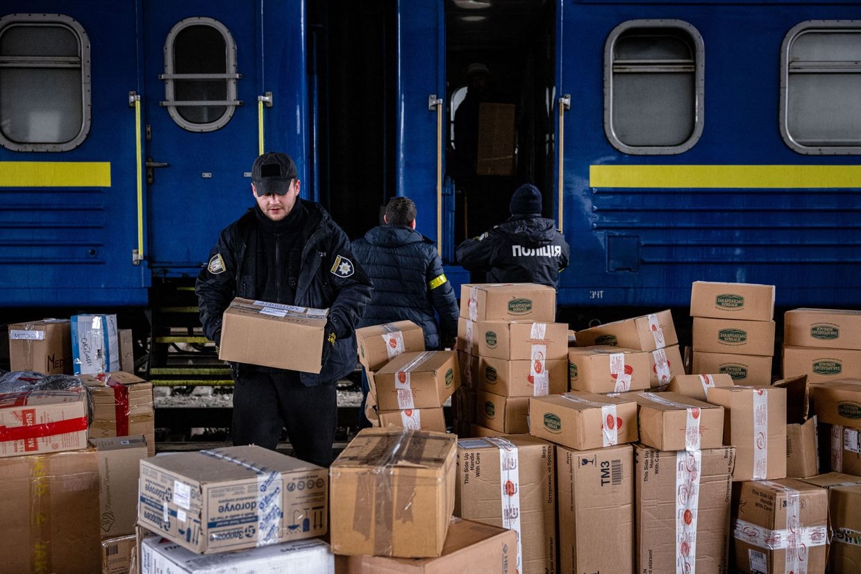 Ukrainian police officers help volunteers unload a train bringin aid to Kyiv's central railway station on March 3, 2022.