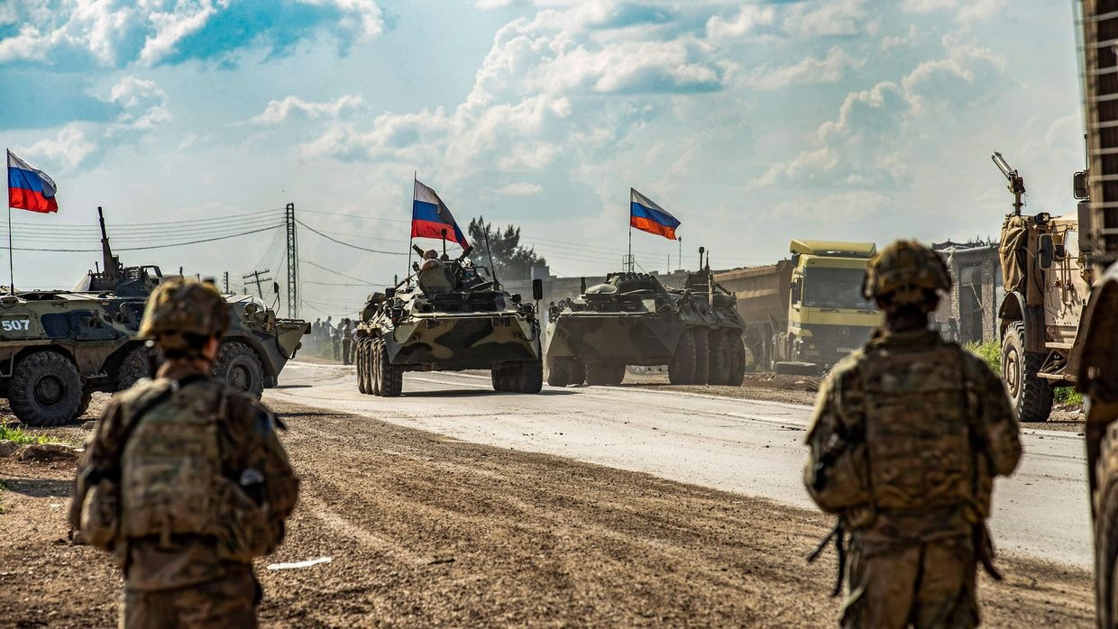 U.S. soldiers stand across from Russian armored personnel carriers near Tannuriyah, Syria, on May 2, 2020.