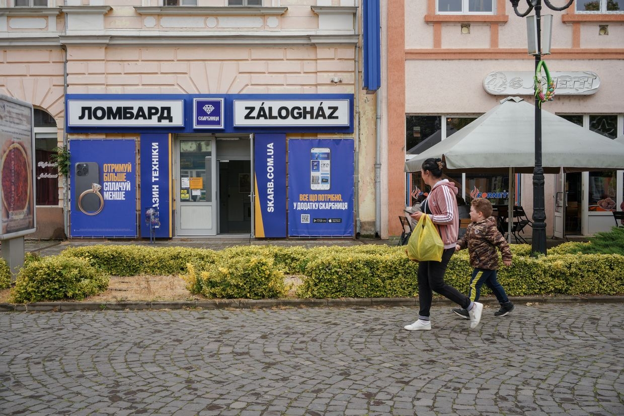 People walk past the bilingual sign in Ukrainian and Hungarian in the center of Berehove, Zakarpattia Oblast, Ukraine on May 22, 2025.