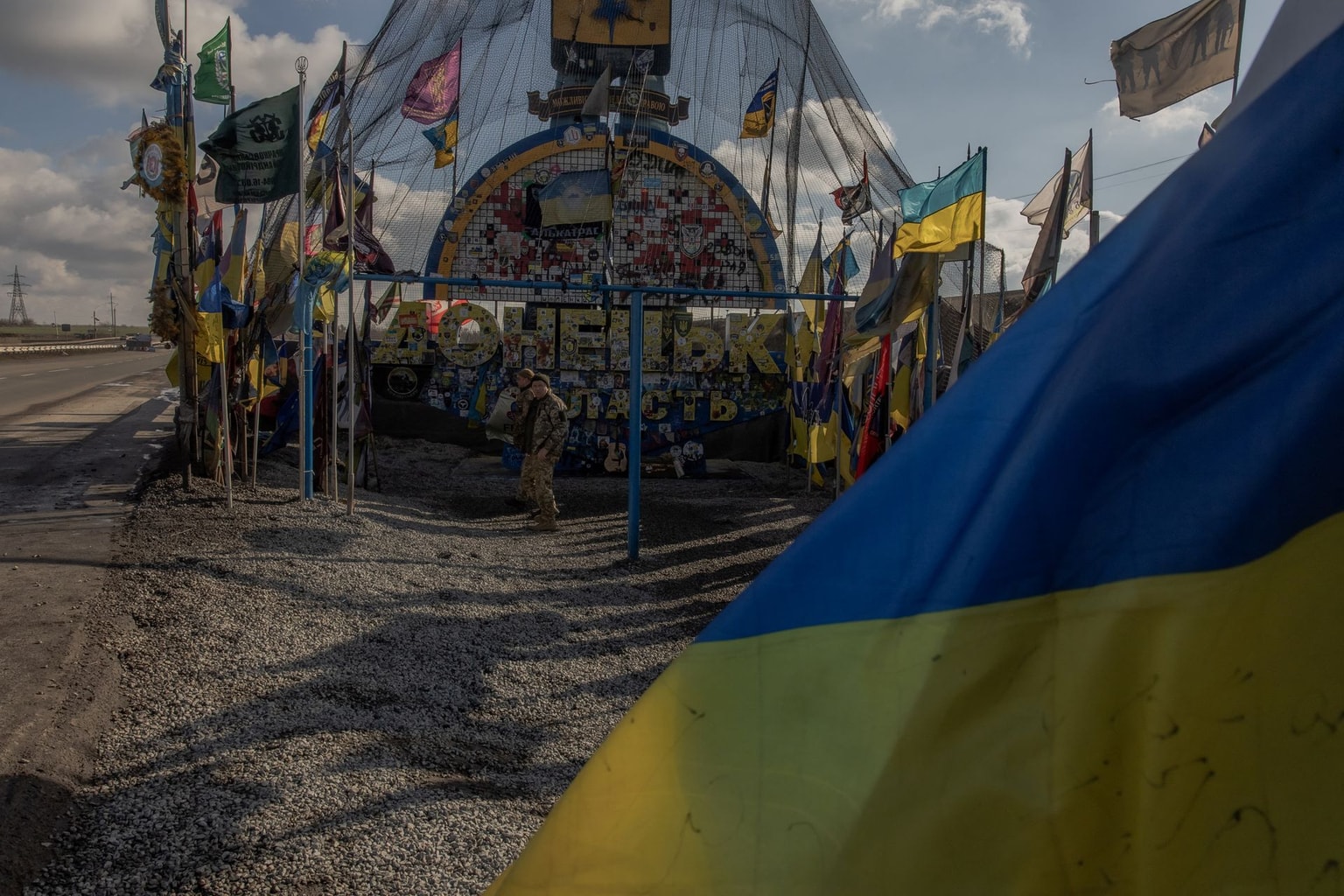Donetsk Oblast entrance sign, protected by anti-drone netting and surrounded by Ukrainian brigade flags, on Feb. 2, 2025.