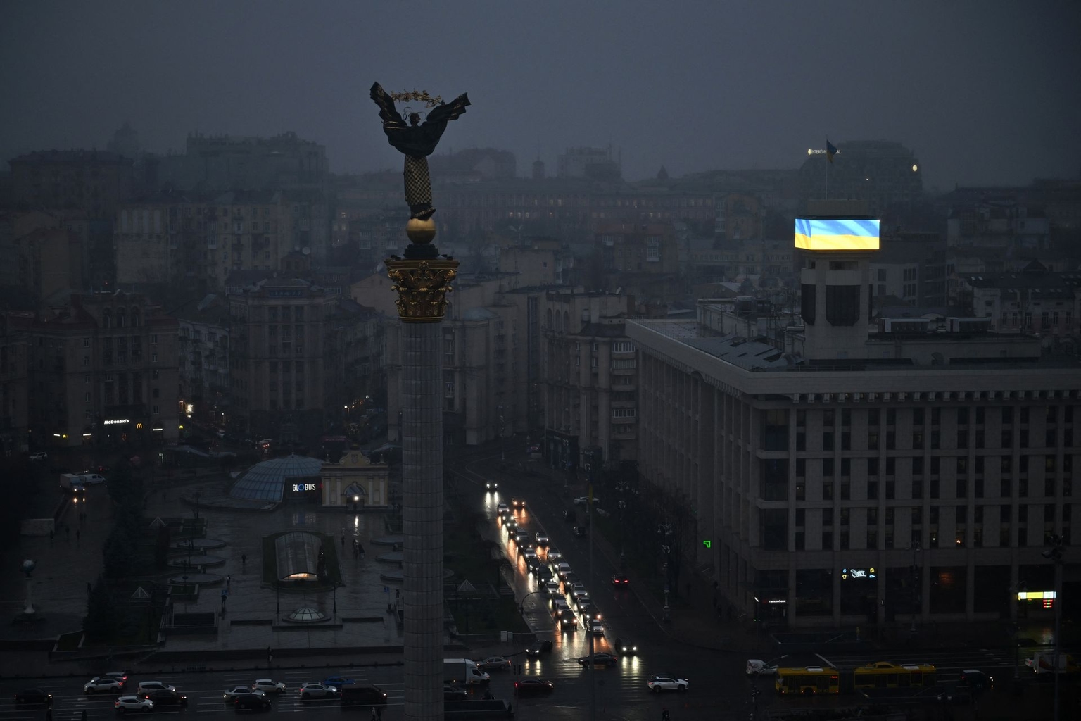 Cars drive through Independence Square as a Ukrainian flag is displayed on a large screen during a power outage in Kyiv, Ukraine, on Nov. 20, 2025.