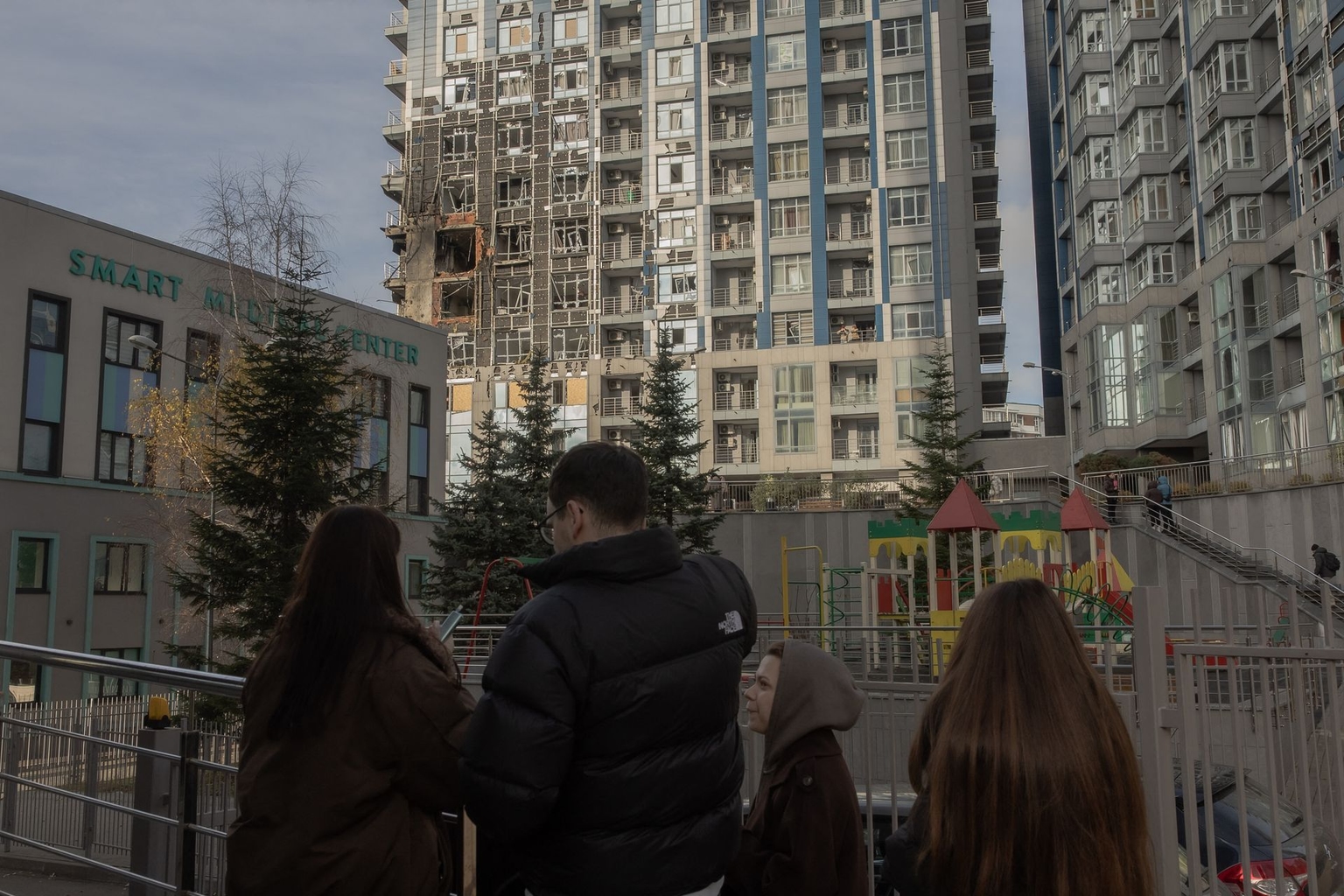 People stand outside a damaged residential building following missile and drone strikes in Kyiv, Ukraine, on Nov. 25, 2025.