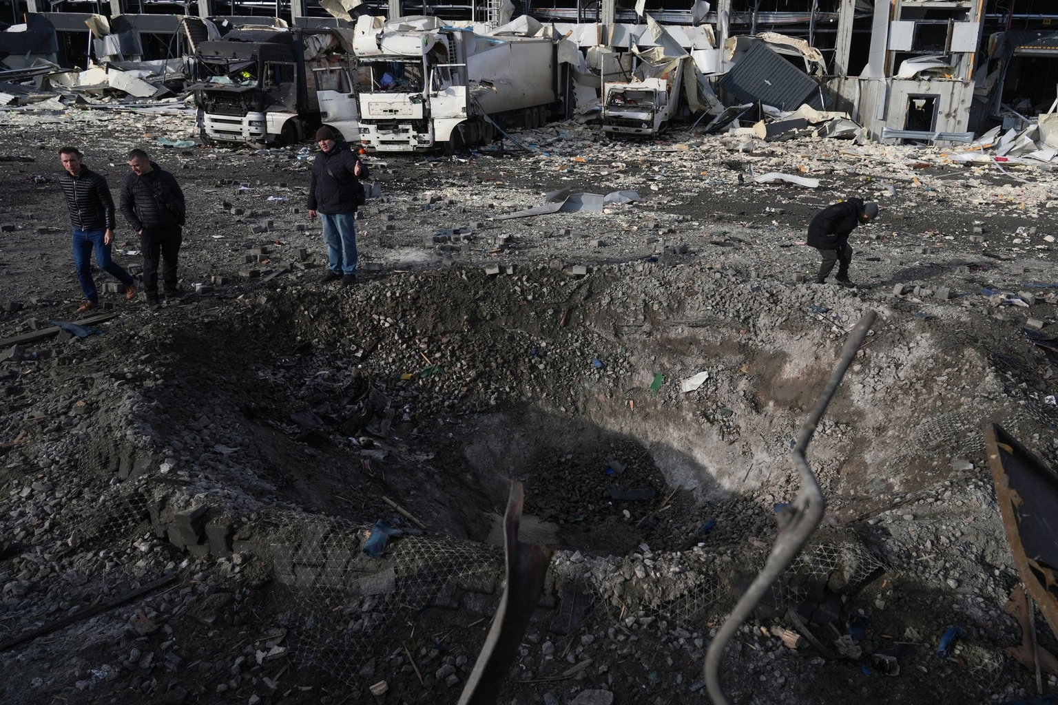 Law enforcement officers inspect a crater next to the heavily damaged Novus supermarket logistics hub following Russian missile and drone strikes in Kyiv, Ukraine, on Nov. 25, 2025.