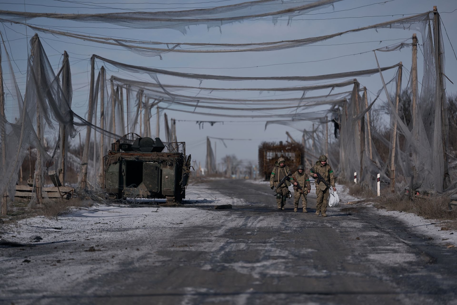 Three infantry servicemen walk along the road between Druzhkivka and Kostiantynivka toward front-line positions near Kostiantynivka in Donetsk Oblast, Ukraine, on Feb. 11, 2026.