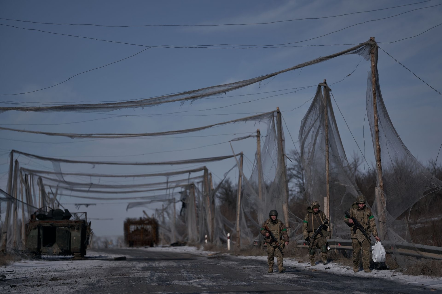 Three infantry servicemen of the 28th Separate Mechanized Brigade walk along a road between Druzhkivka and Kostiantynivka in Donetsk Oblast, Ukraine, on Feb. 11, 2026.