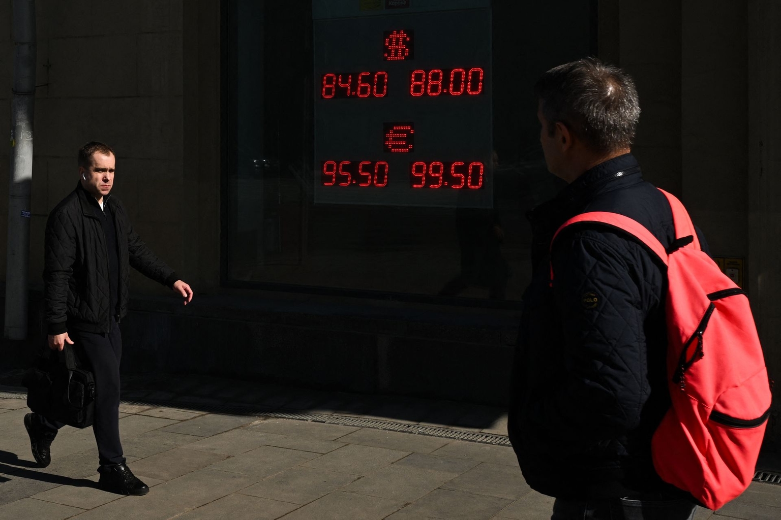 Men walk past a currency exchange office in Moscow, Russia, on March 19, 2026.
