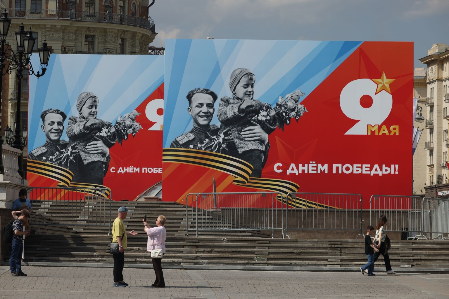 People walk by Victory Day parade billboards in Moscow, Russia, on May 7, 2026.
