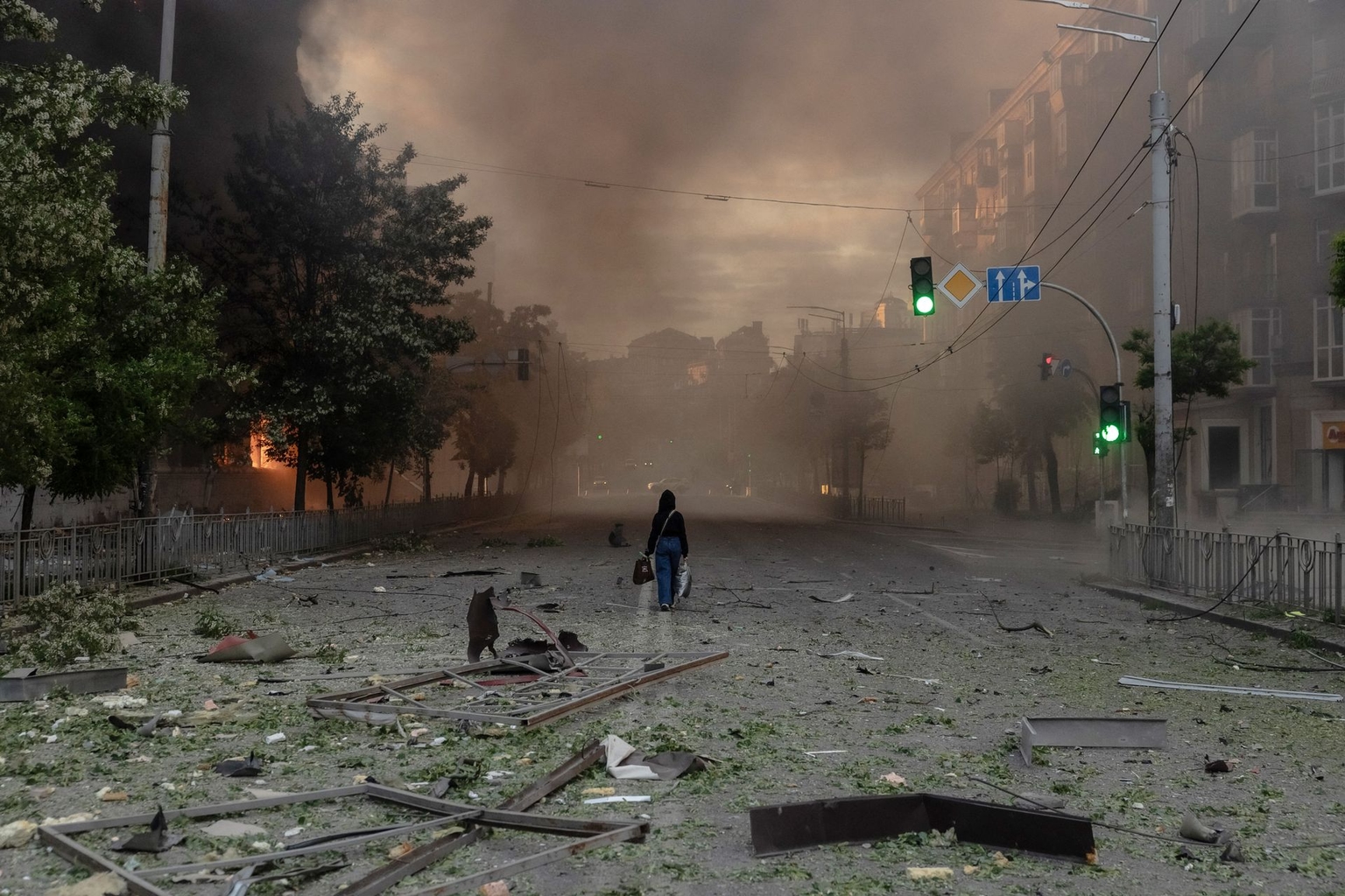 A woman walks along a smoke-filled road past heavily damaged buildings following Russian strikes in Kyiv, Ukraine, on May 24, 2026.
