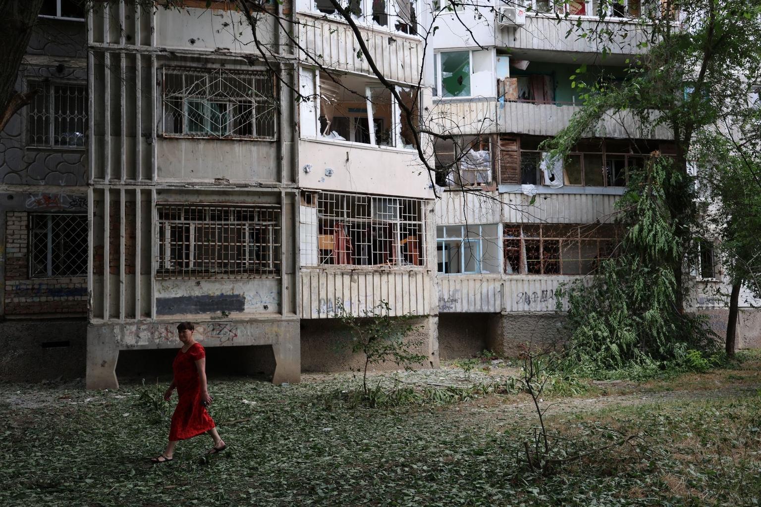 A woman walks past a residential building damaged by Russian shelling in Kherson, Ukraine, on June 21, 2025.