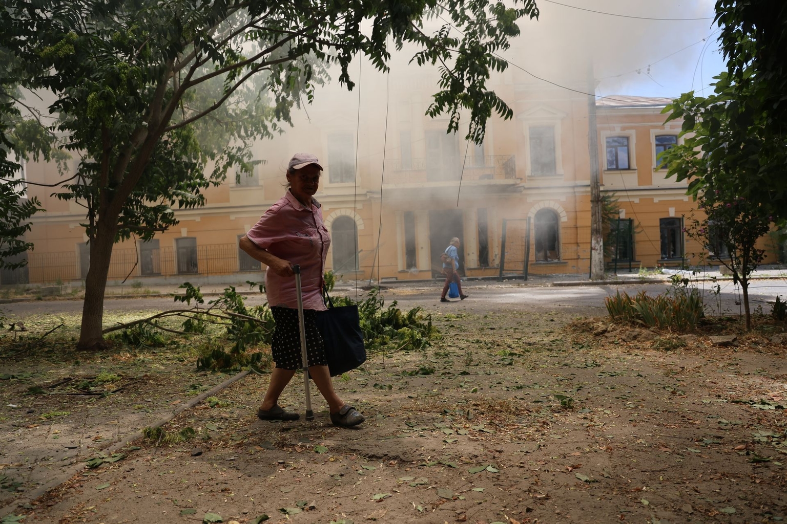 People walk along a street past a burning House of Culture hit by Russian shelling in Kherson, Ukraine, on July 14, 2025.