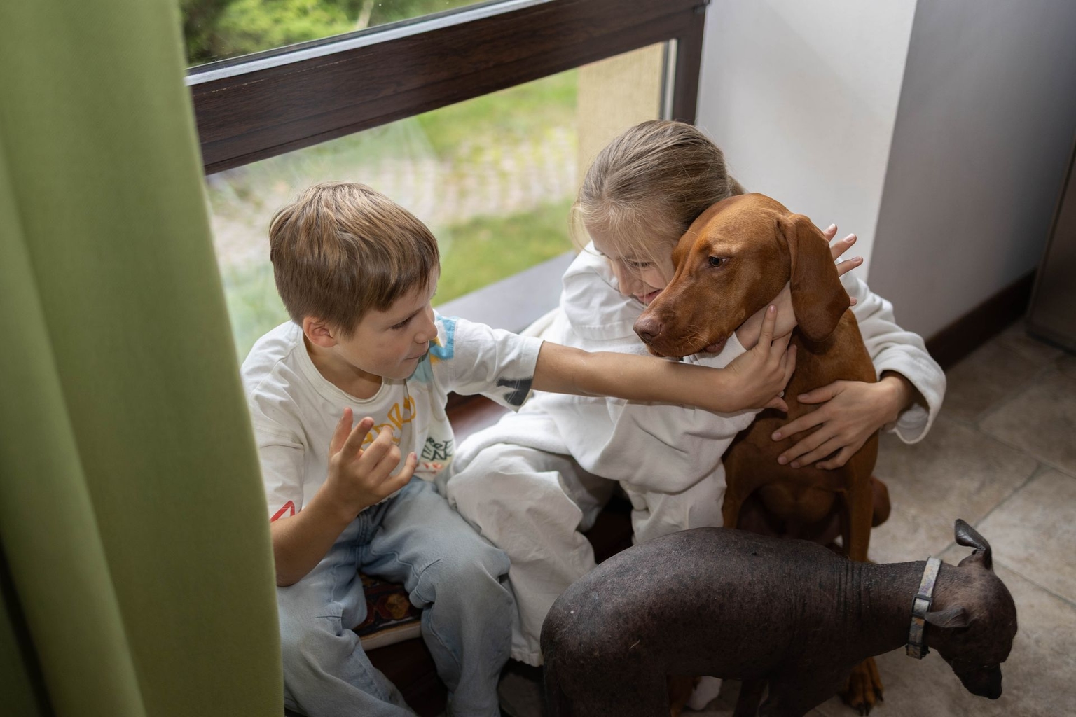 Myroslava and Andriiko with their rescued dog, Hugo (ginger), and their dog Mimi in Bobrytsia, Kyiv Oblast, Ukraine, on Oct. 22, 2025.