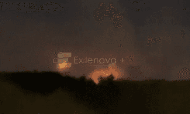 A fire burns in the distance under a night sky