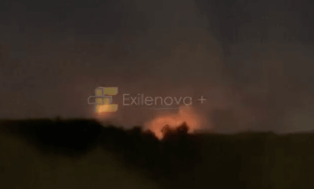 A fire burns in the distance under a night sky