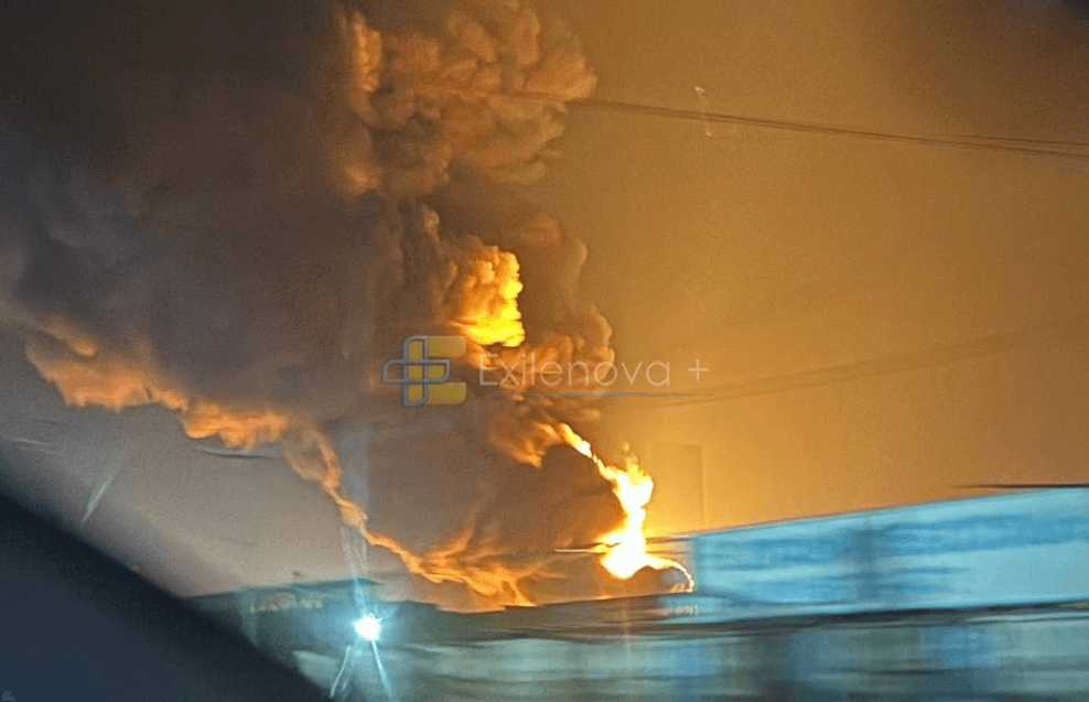 Heavy smoke rises under a night sky illumninated by a fire below
