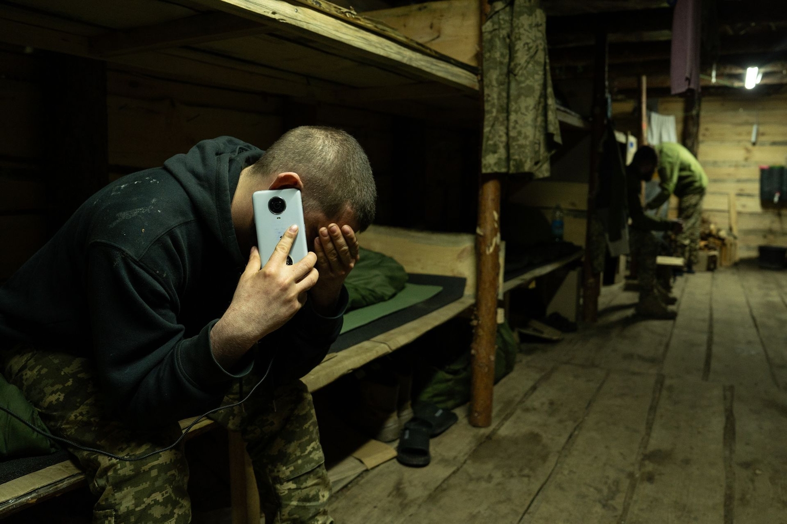 Mykhailo, 28, talks on the phone with his wife in a dugout in Kharkiv Oblast, Ukraine, on April 2, 2026.