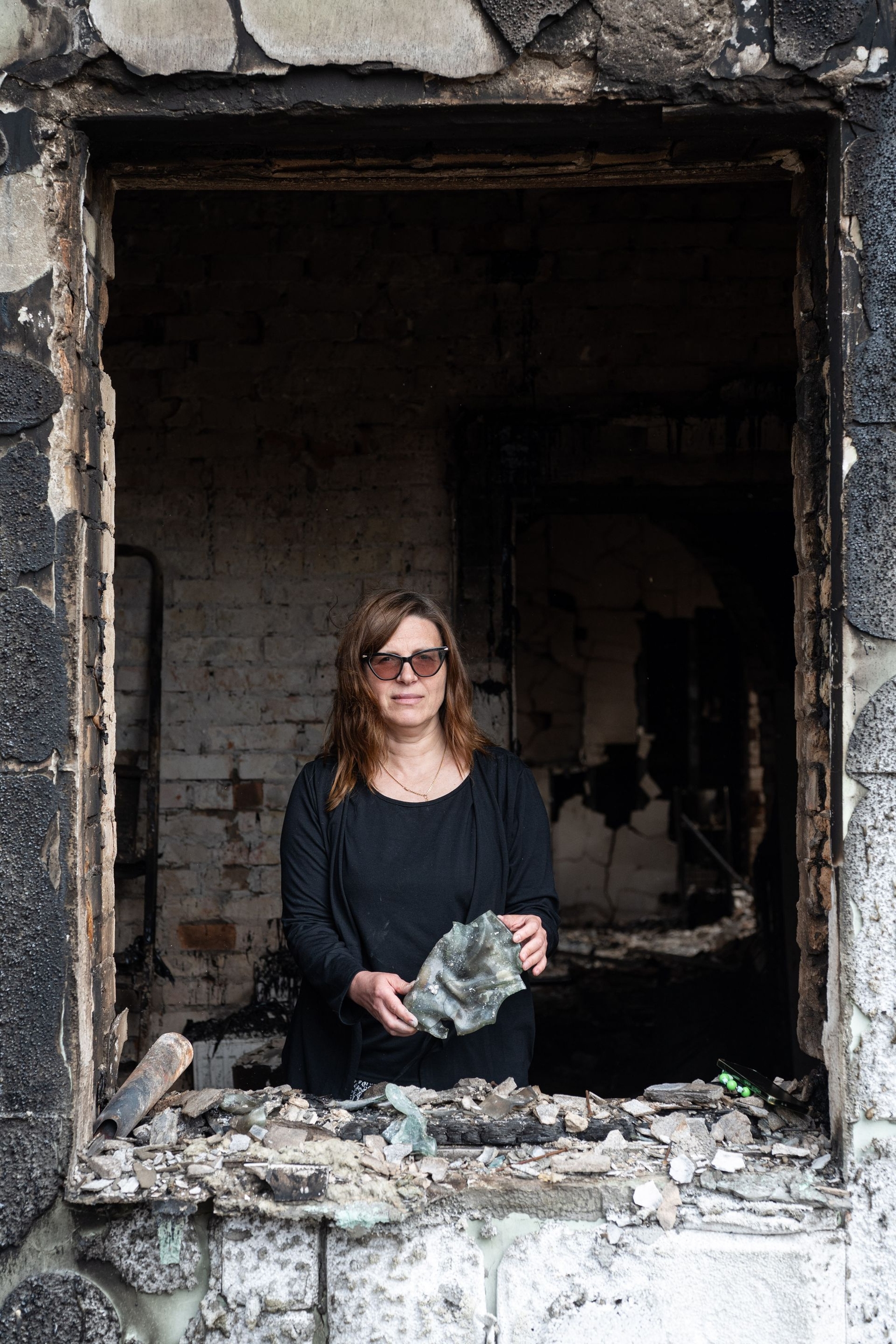 Anna Kuzmenko, 53, poses for a portrait inside her destroyed house in Vyshneve, Kyiv Oblast, Ukraine, on July 3, 2026