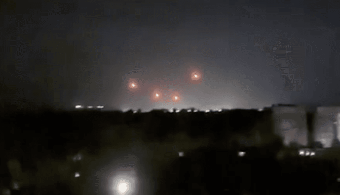 Four air defense missiles light up orange under the night sky