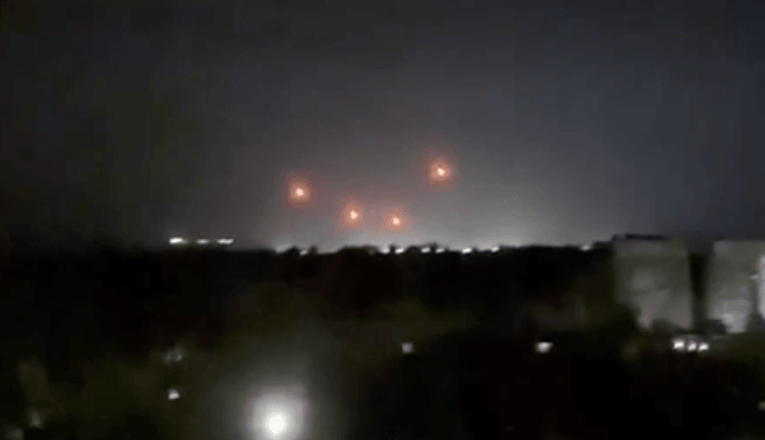Four air defense missiles light up orange under the night sky