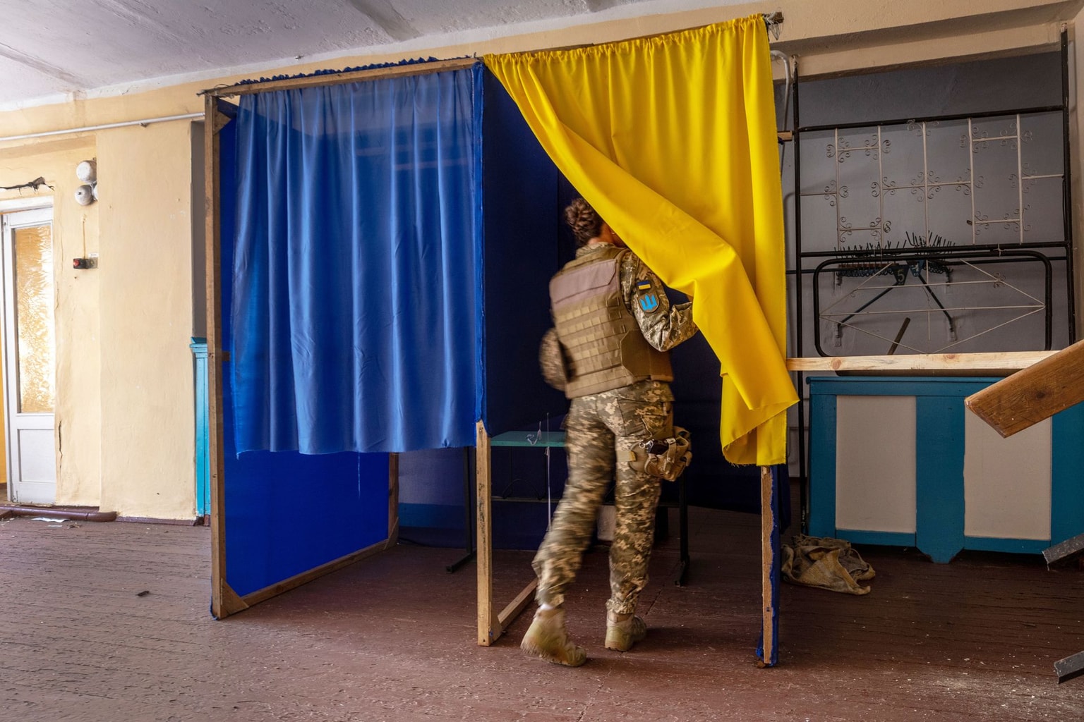 A Ukrainian soldier checks a voting booth at a damaged school in Zagradivka, Ukraine, on May 8, 2022.