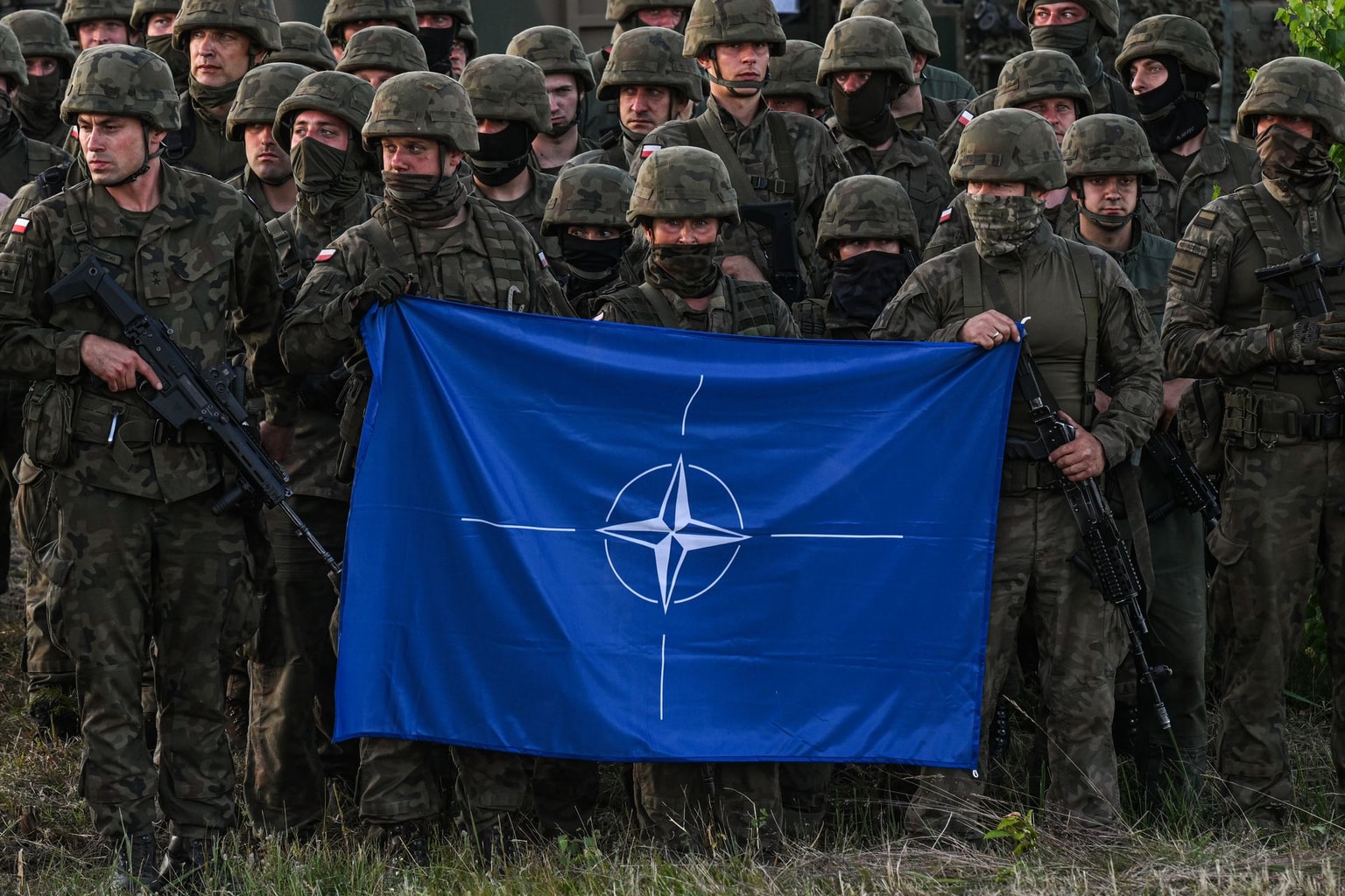 Polish soldiers hold a NATO flag at the Orzysz training ground in Orzysz, Poland, on July 3, 2022.