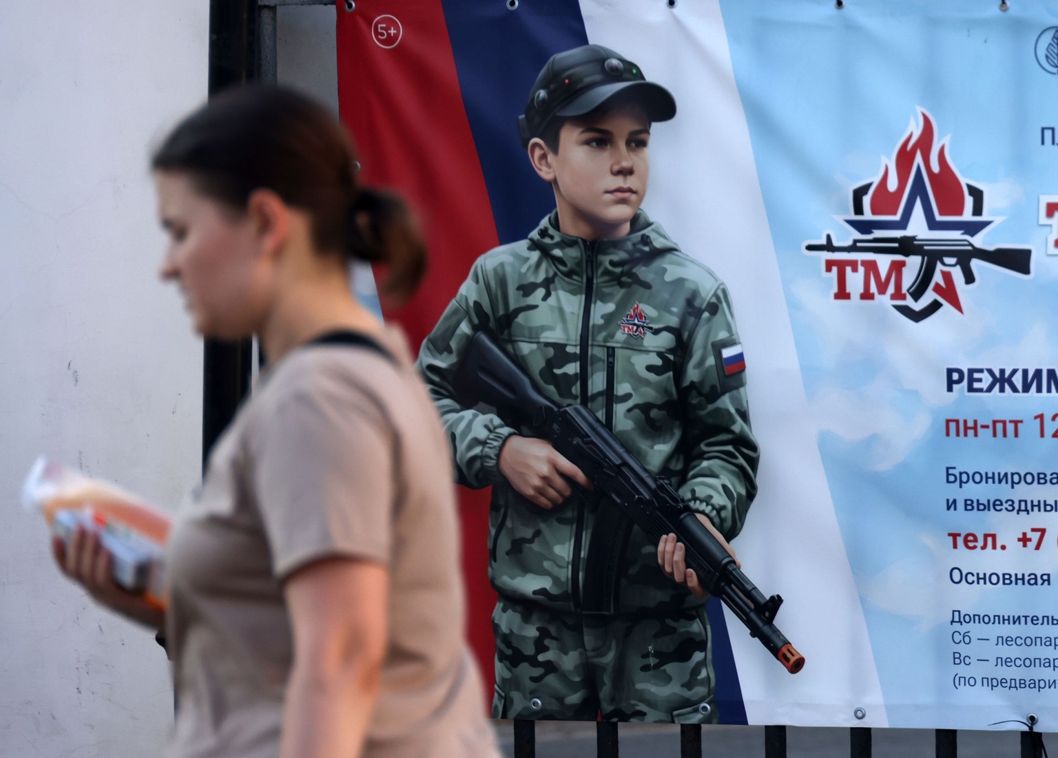 A woman walks past a military-patriotic playground poster in Dedovsk, Russia, on August 6, 2026.