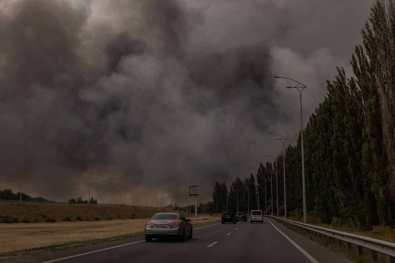 Cars drive on a road as smoke rises in the distance from a warehouse following a Russian air attack near Boryspil, Kyiv Oblast, Ukraine, on Aug. 27, 2026.