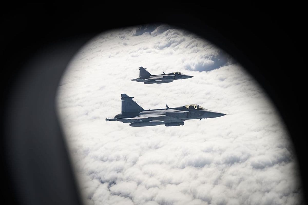 Two Swedish Air Force Saab JAS 39 Gripen fighter jets prepare to take on fuel from a British Voyager aircraft.