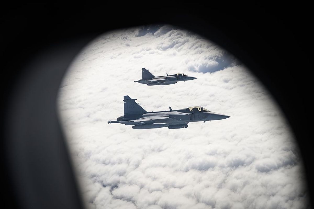 Two Swedish Air Force Saab JAS 39 Gripen fighter jets prepare to take on fuel from a British Voyager aircraft.