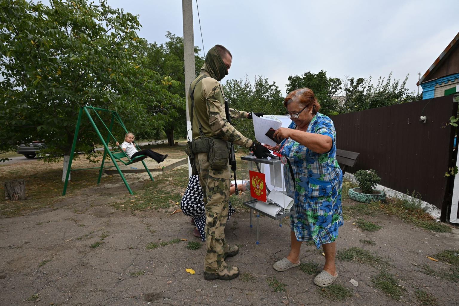 A woman casts a ballot into a mobile box held by a Russian serviceman in Verbivka, Russian occupied part of Ukraine, on September 14, 2026.