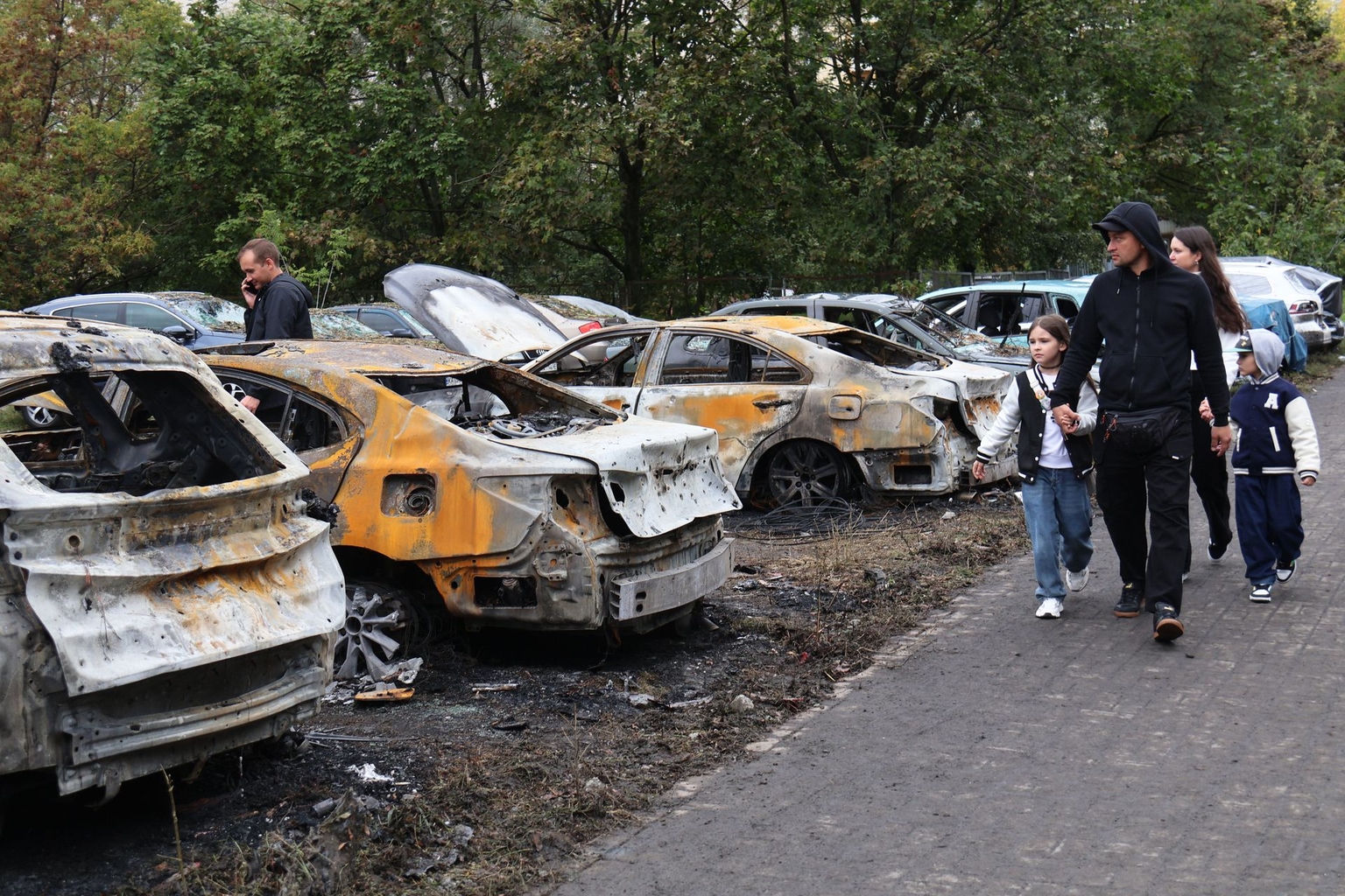 People walk past burnt-out cars in Kyiv, Ukraine, on Sept. 24, 2026.