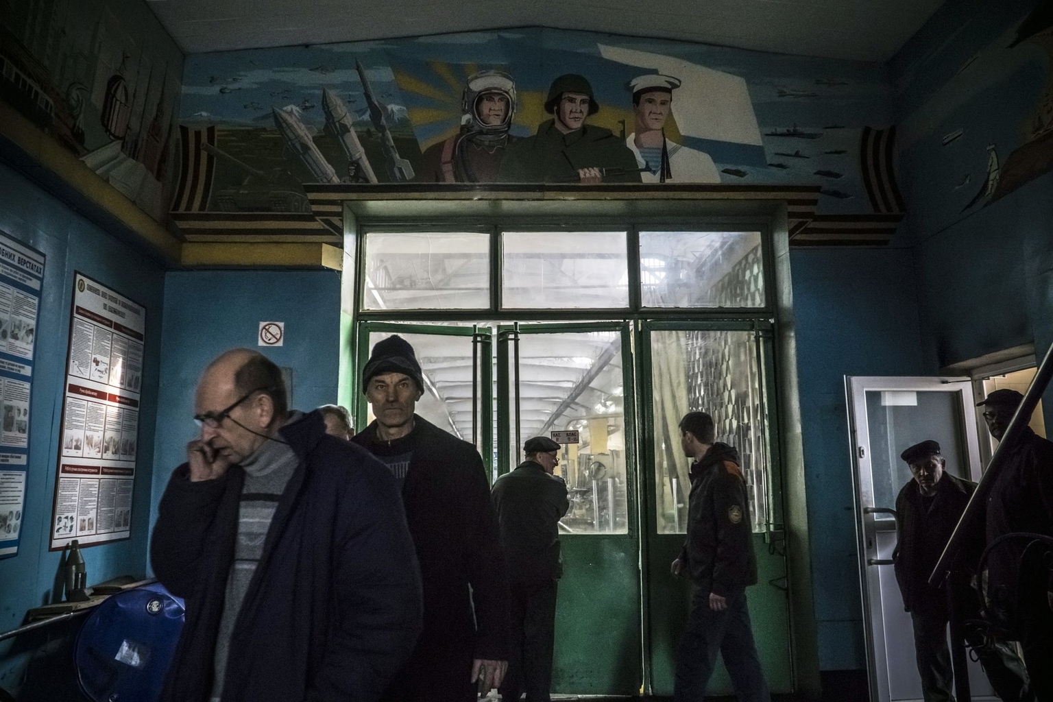 Workers pass beneath a Soviet-era military mural at an Ukroboronprom workshop in Lviv, Ukraine, on February 15, 2016.