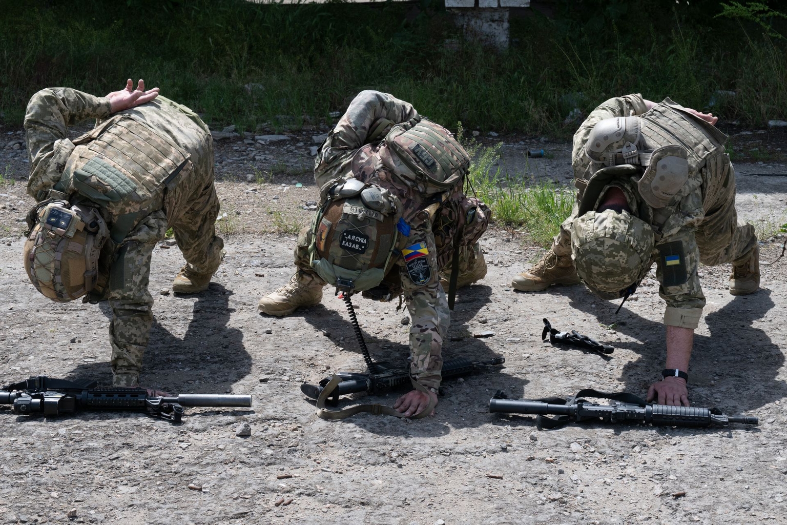 Three Bolivar Battalion soldiers do one-arm push-ups in Mykolaiv Oblast, Ukraine, in May 2026.