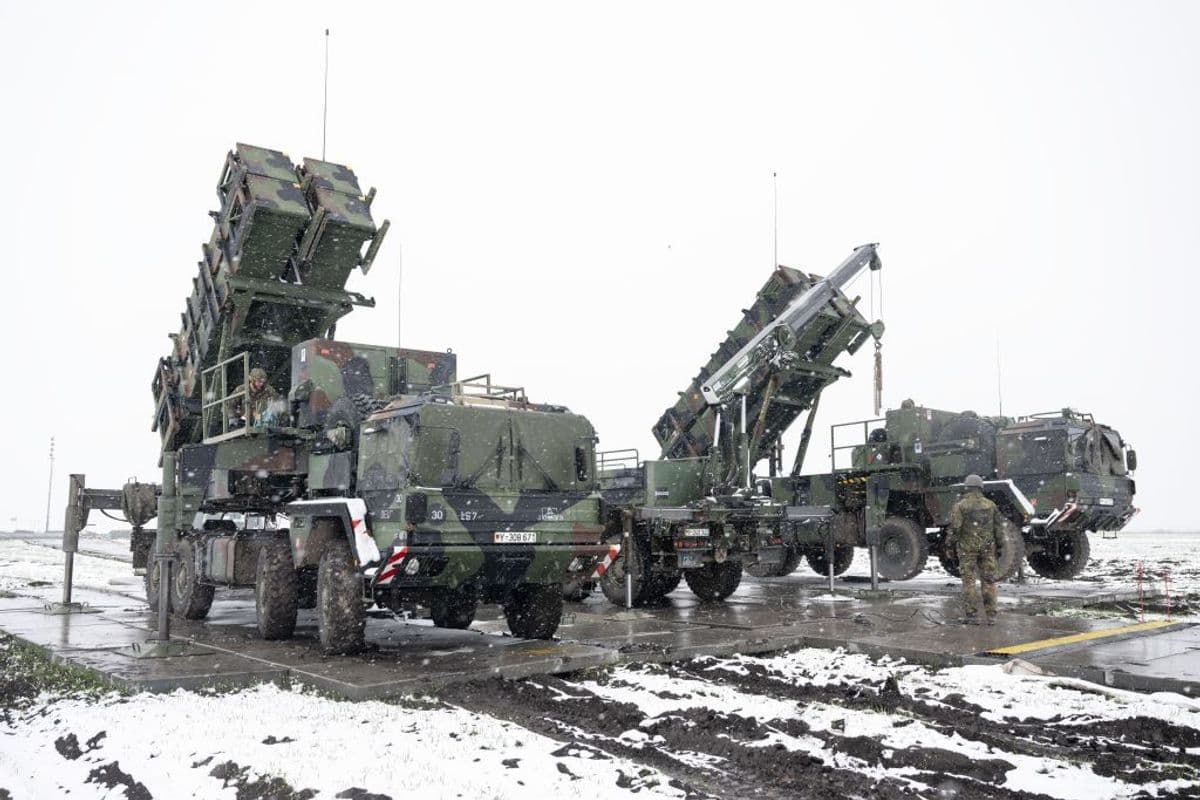 Bundeswehr soldiers work on a crane between trailers with Patriot missile launchers.