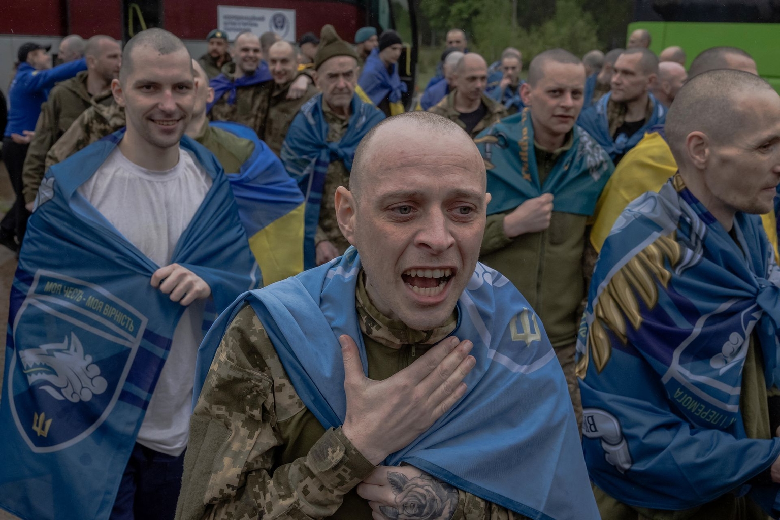 Ukrainian POWs wrapped in Ukrainian national flags react following a prisoner exchange at an undisclosed location in Chernihiv Oblast, Ukraine, on May 15, 2026.
