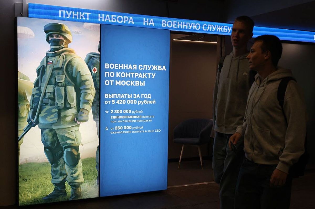 Men walk past a military contract enlistment point in a metro station underpass in Moscow.
