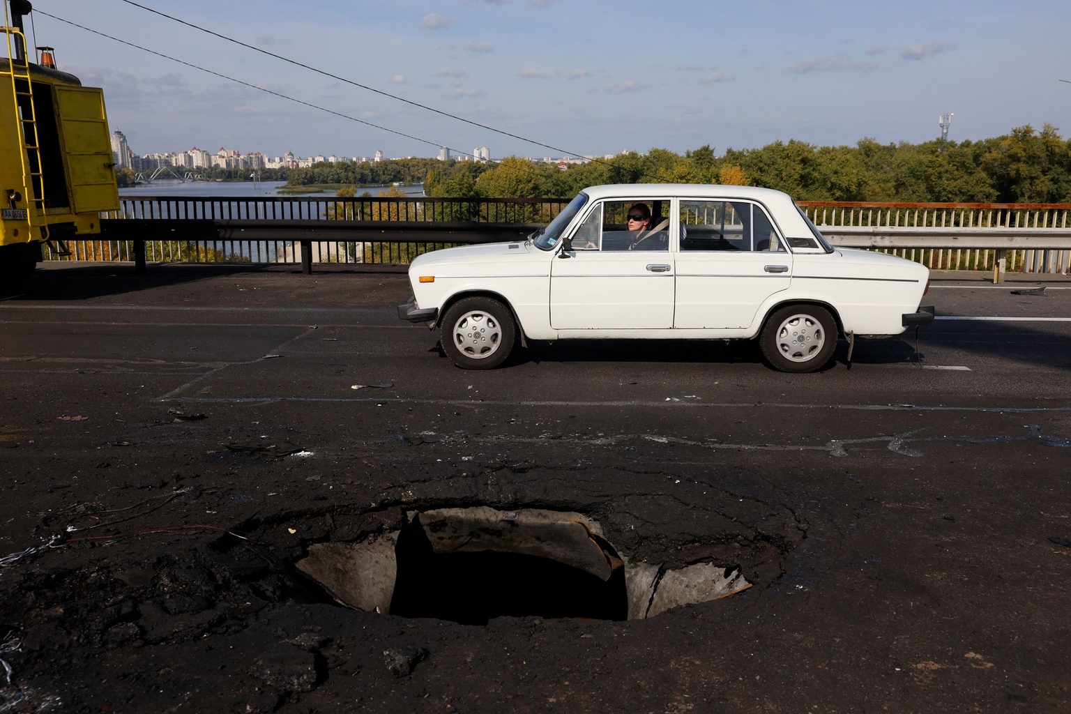 A car drives past a hole in the bridge in Kyiv, Ukraine, on Oct. 4, 2026.